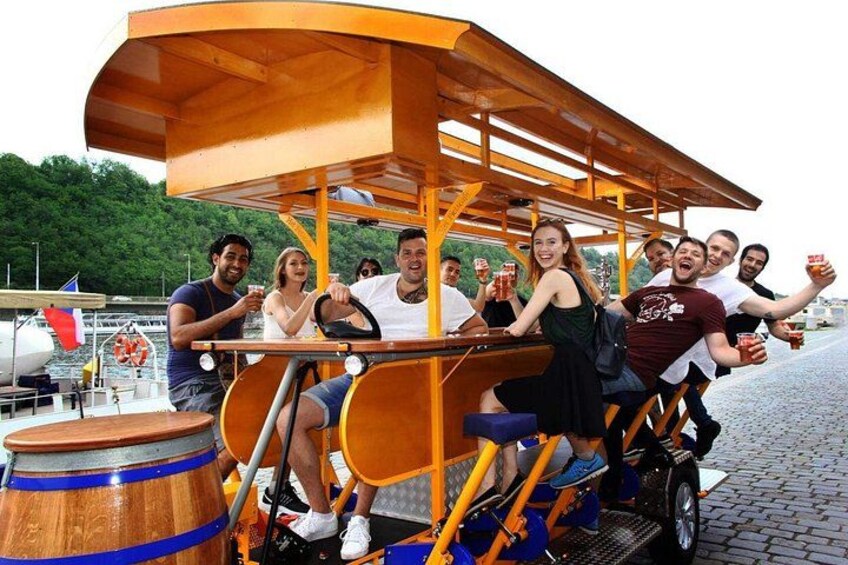 A group of people on a wooden cart with a canopy, on a cobblestone path. 1