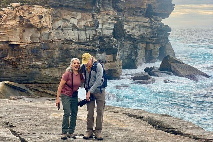 Deux personnes se tiennent debout sur une falaise rocheuse, au bord de l’océan. 1