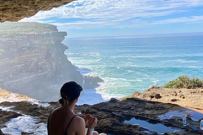 Una persona de pie en un acantilado rocoso, con vistas a una zona costera con riscos y el océano. 1
