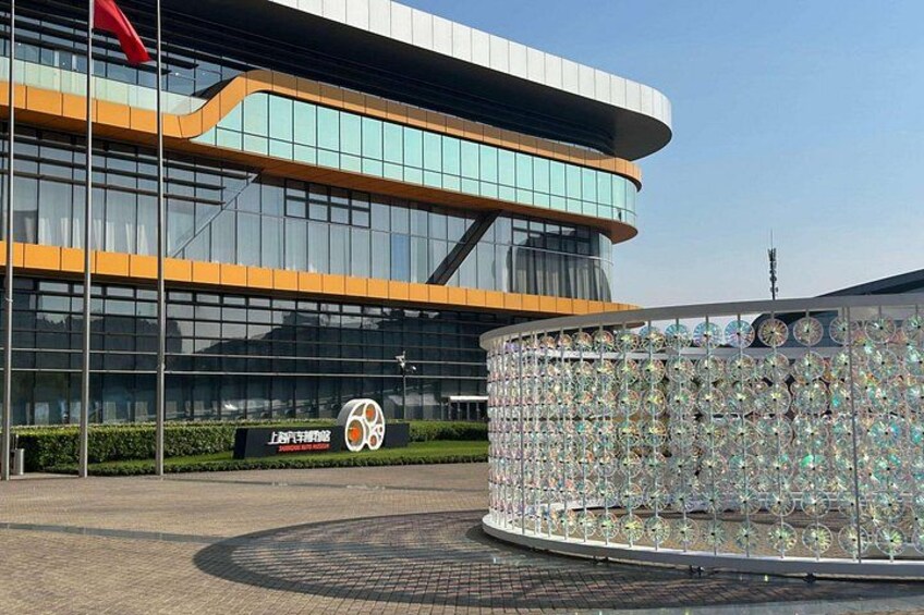 A modern building with reflective glass windows, a circular decorative structure with mirrors, and a sign with a number. 5