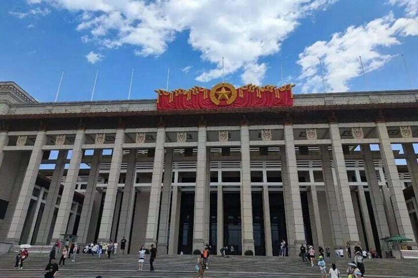 A large building with a prominent red banner and a golden emblem on the facade. 1