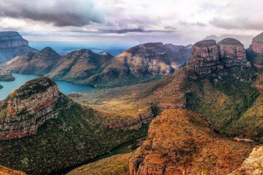 A mountainous landscape with a river, cliffs, and a lake. 1