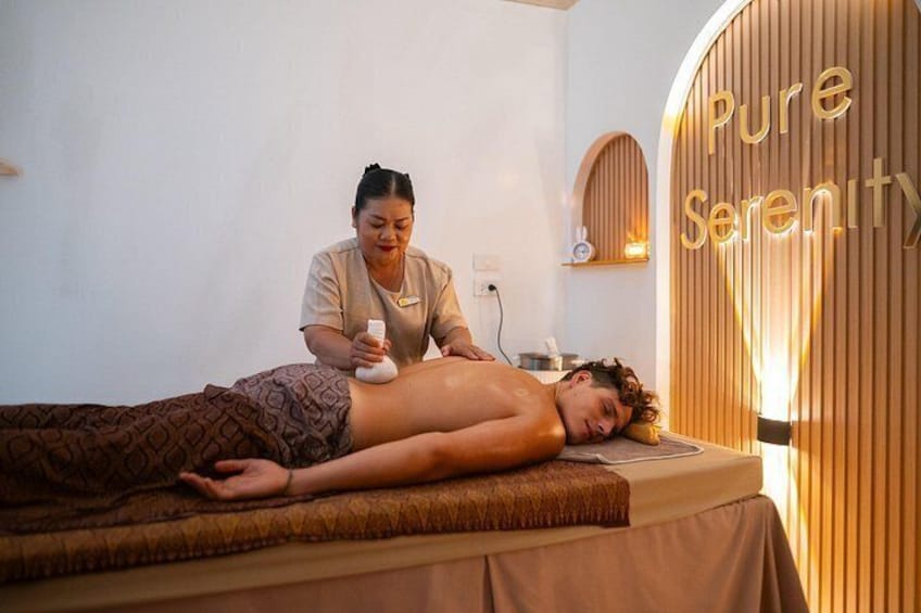 A person receiving a massage in a room with a wooden wall and a sign that reads 'Pure Serenity'. 2