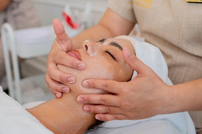 A person receiving a facial treatment with hands applying a substance to the face. 5