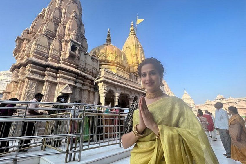 A person in traditional attire standing in front of a temple with intricate architecture. 5