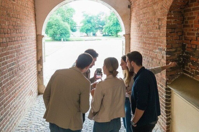 A group of people standing in a brick corridor with an arched entrance leading outside. 2