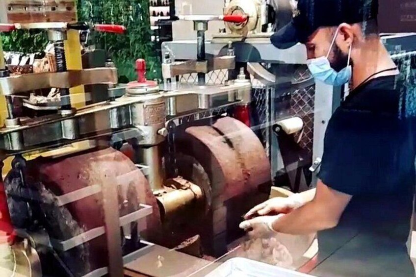 A person operating a large industrial machine, possibly a meat grinder, in a workshop or factory setting. 3