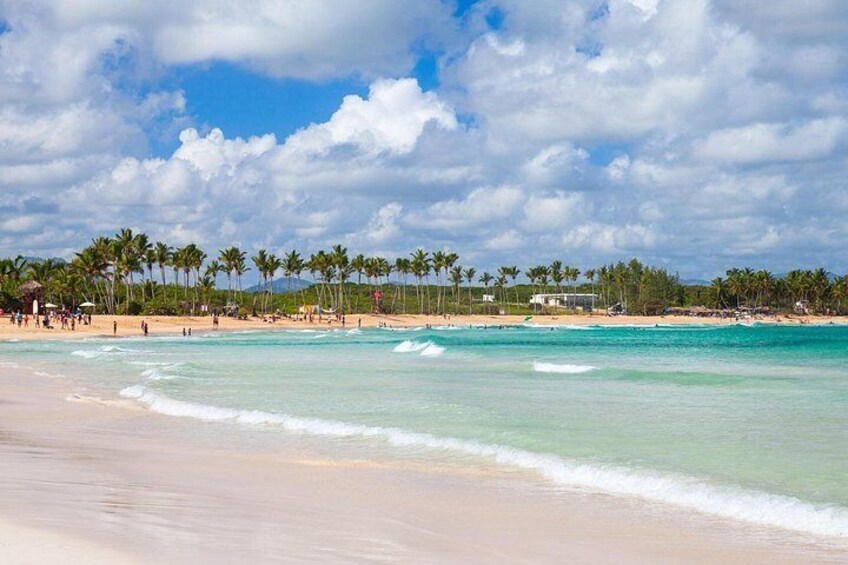 A beach with clear turquoise water, palm trees, and a few people. 5