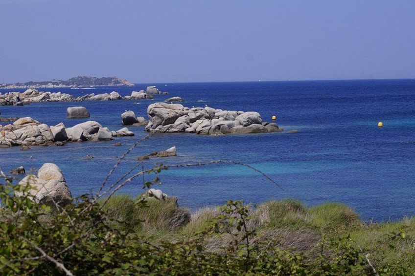 A coastal landscape with large rocks and clear blue water. 3
