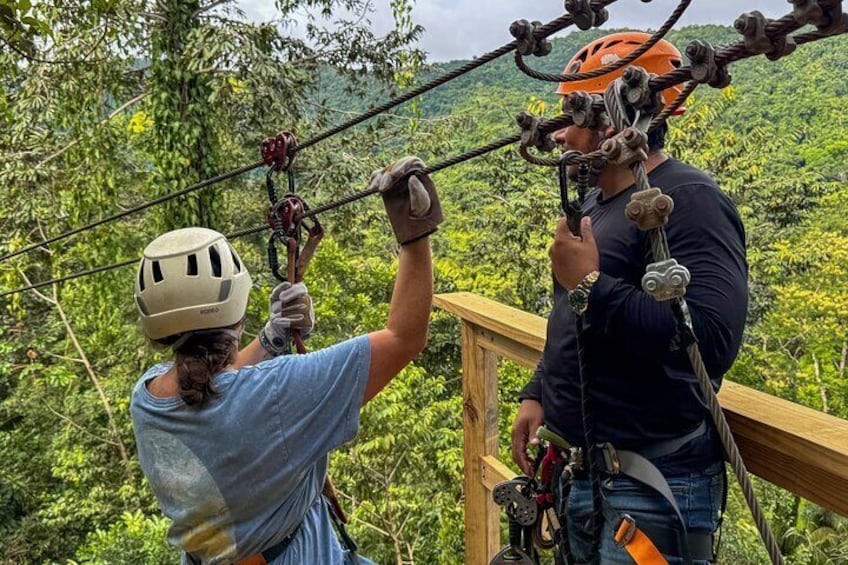 Dos personas con casco y arnés preparándose para practicar tirolesa. 1