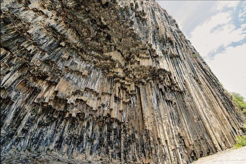 A large, rugged rock formation with layered textures and a steep incline. 2