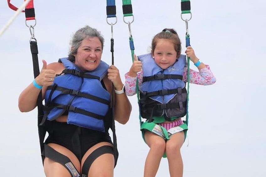 Two people on a swing ride, wearing life jackets and holding onto the bars. 2