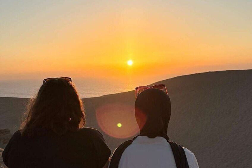Two people overlooking a sunset over a beach. 4