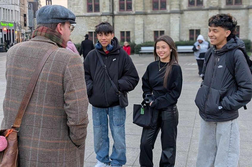 Un grupo de personas de pie al aire libre en un entorno urbano con edificios al fondo. 4