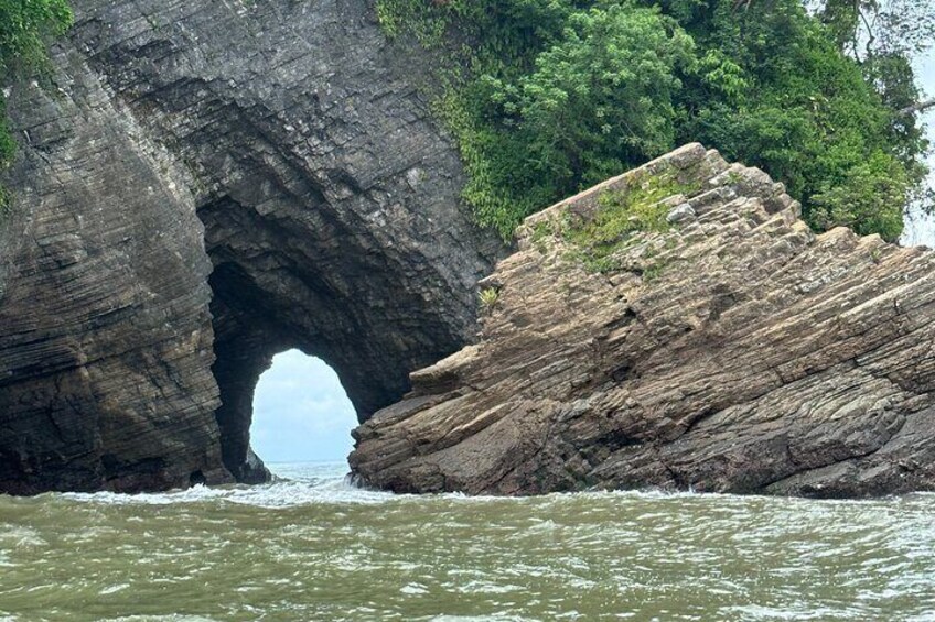 Una formación natural de arco de roca sobre una masa de agua, rodeada de abundante vegetación. 5