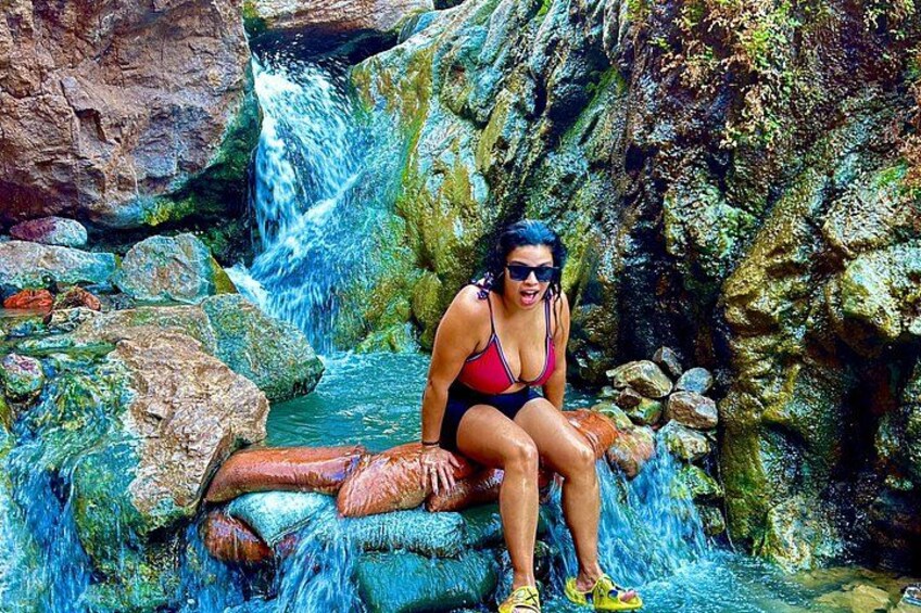 A person sitting on rocks by a waterfall. 2