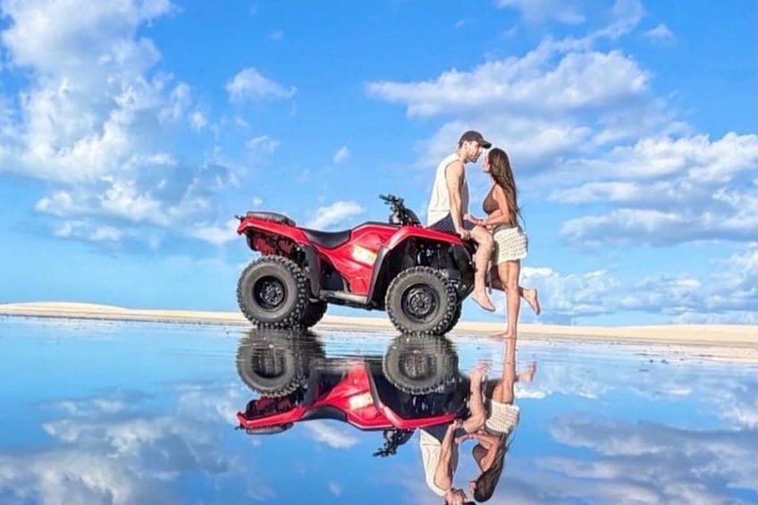 A red ATV on a reflective water surface with a couple standing beside it. 2