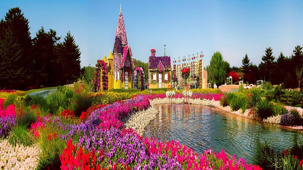 A garden with a pond, colorful flowers, and a whimsical building with a pointed roof. 2