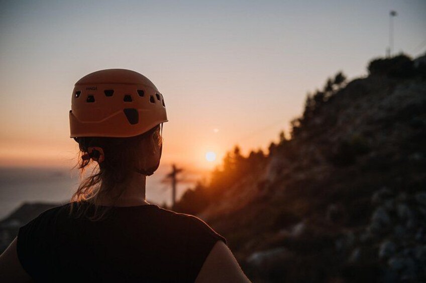 Una persona con casco, contemplando un atardecer sobre un paisaje rocoso. 5