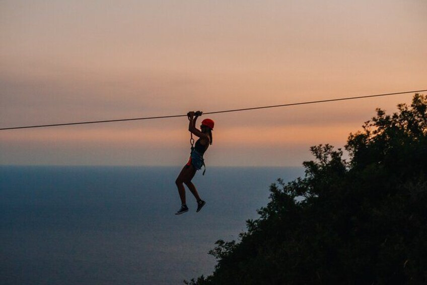 En person abseiler ned ad en wire med solnedgang i baggrunden. 4