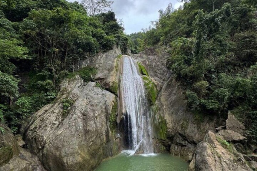 A waterfall cascading down a rocky cliff surrounded by dense green foliage. 1