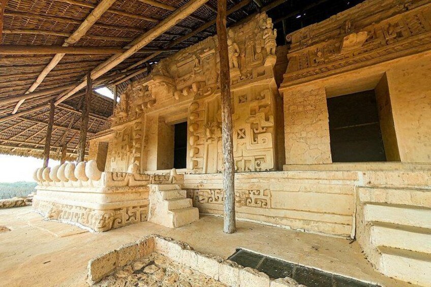 An ancient stone structure with intricate carvings and a thatched roof. 5