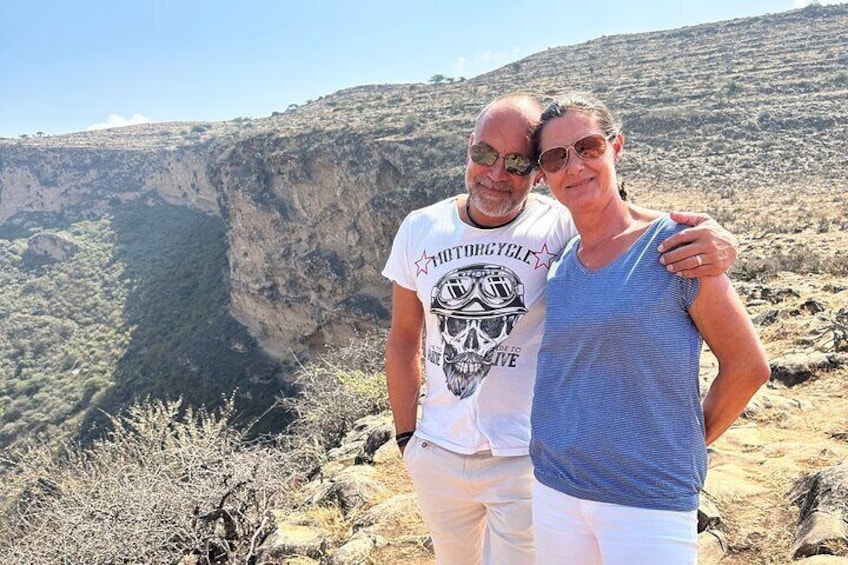 Dos personas de pie sobre un afloramiento rocoso, con un paisaje montañoso al fondo. 2
