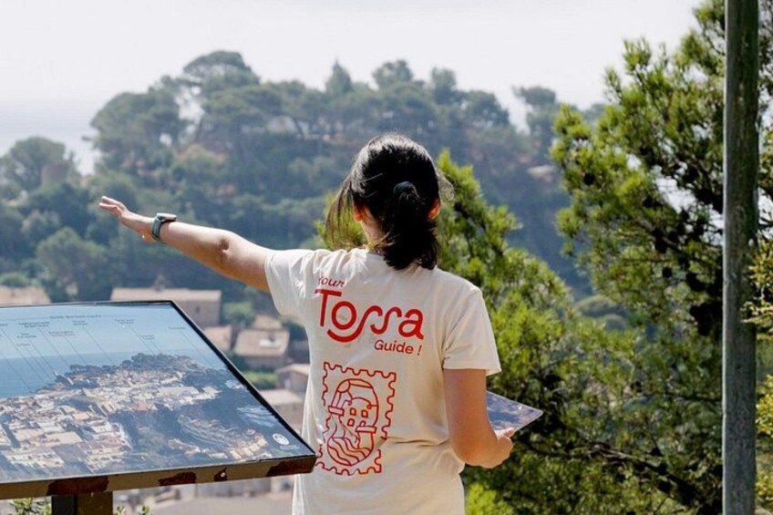 A person wearing a Tossa Guide t-shirt pointing at a map. 4