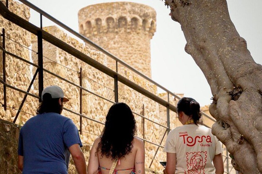 Tourists walking on a stone staircase with a historical tower in the background. 1
