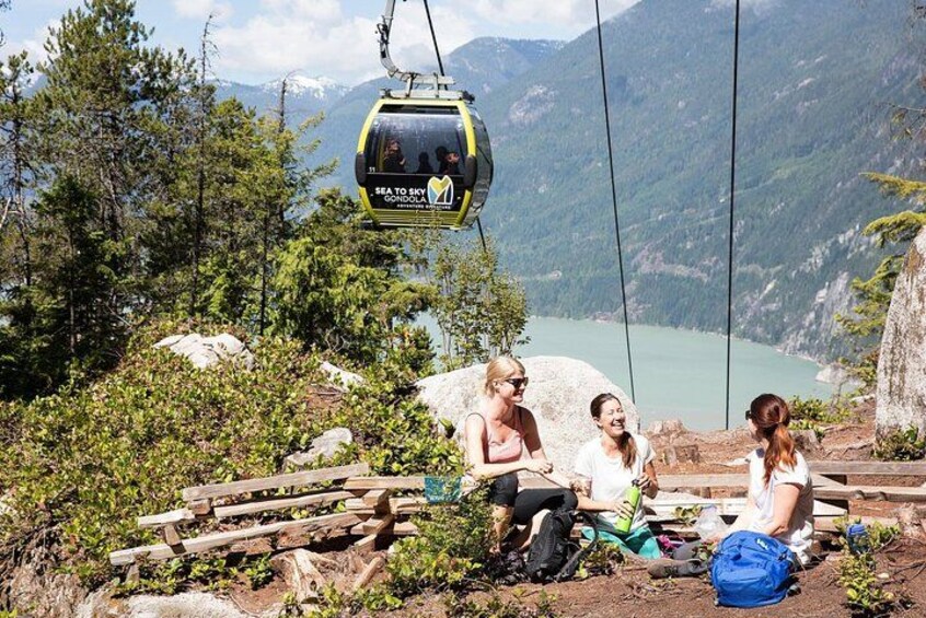 A cable car with passengers, a lake, and mountains in the background. 3