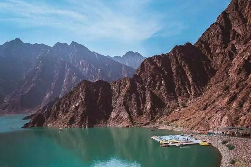 Un paisaje montañoso con un lago turquesa y un muelle con barcas de colores. 1