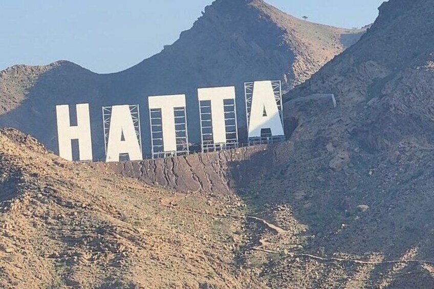 Grandes letras que deletrean 'HATTA' en una ladera rocosa. 3