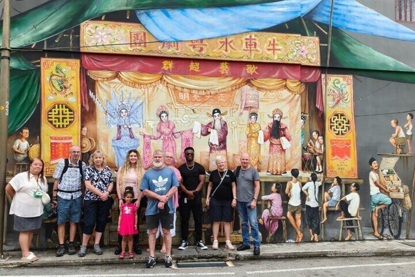 Un gruppo di persone che posa davanti a uno sfondo vivace con esibizioni culturali. 4