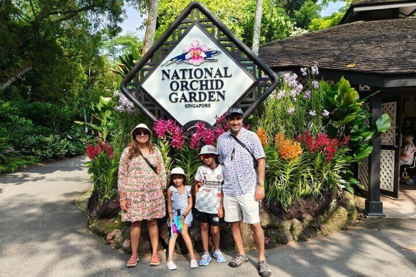 Una famiglia in piedi di fronte al cartello del National Orchid Garden a Singapore. 5
