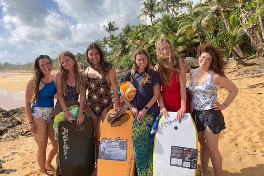 A group of people on a sandy beach with surfboards, palm trees, and a clear sky. 4