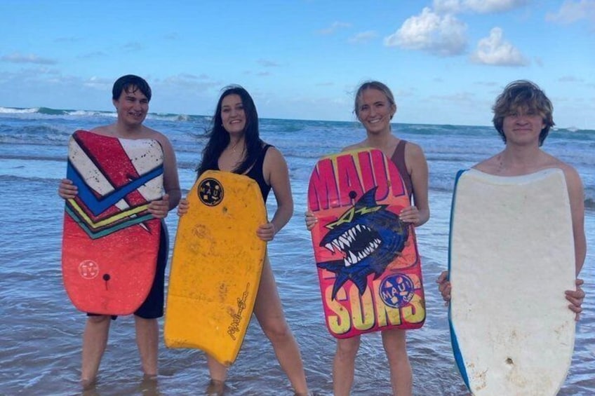 Four people holding surfboards at the beach. 5