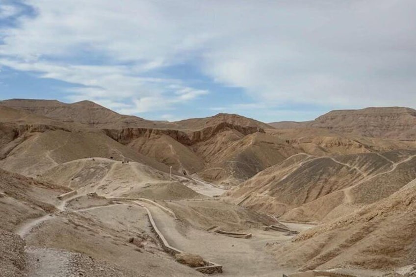 A barren desert landscape with undulating hills and a winding road. 1