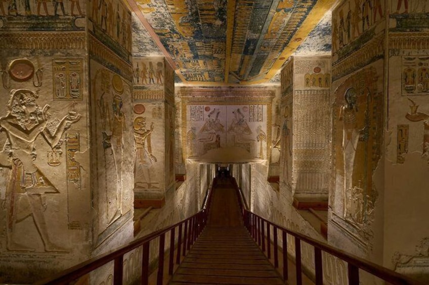 A corridor with hieroglyphs and a staircase leading to a room with a large painting. 3
