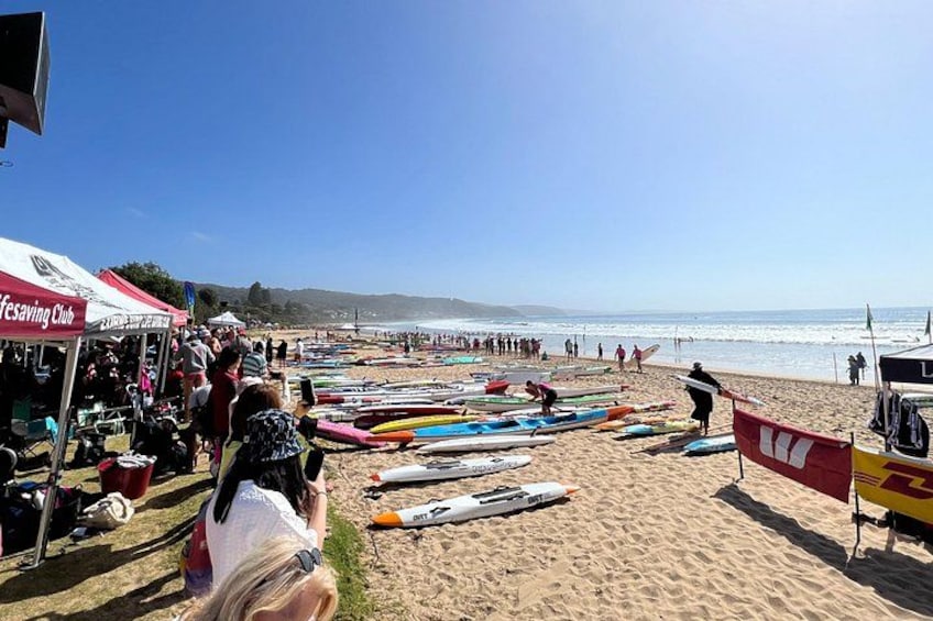 A beach with people, a lifeguard tower, and several colorful kayaks. 2