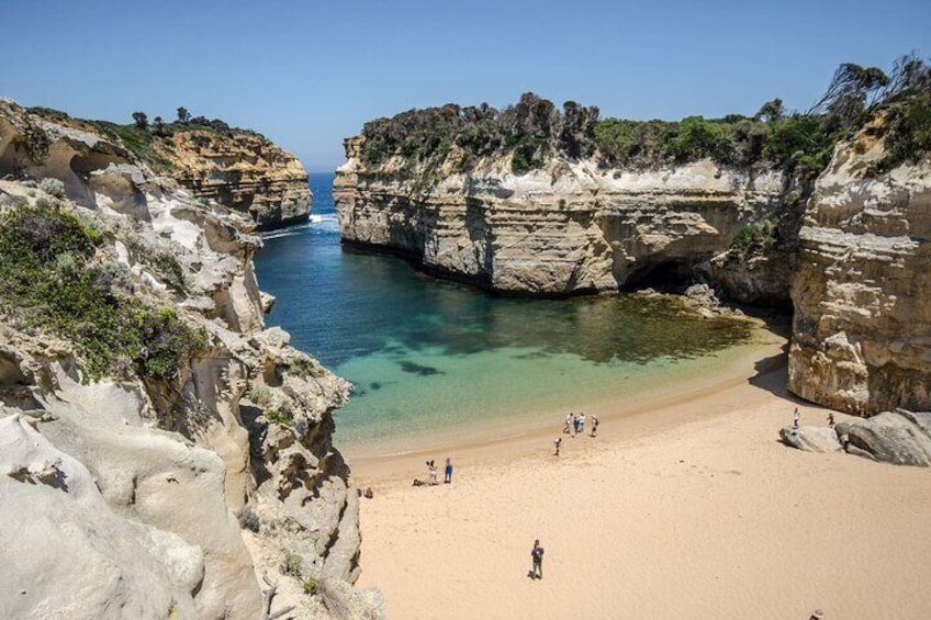 A coastal beach with rocky cliffs and clear turquoise water. 1