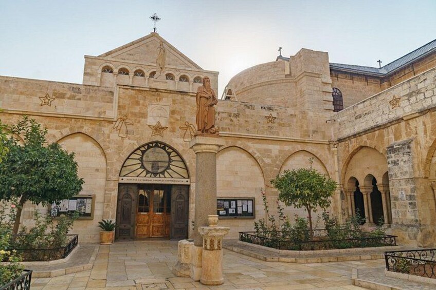 A historic building with arches, a dome, and a statue. 2