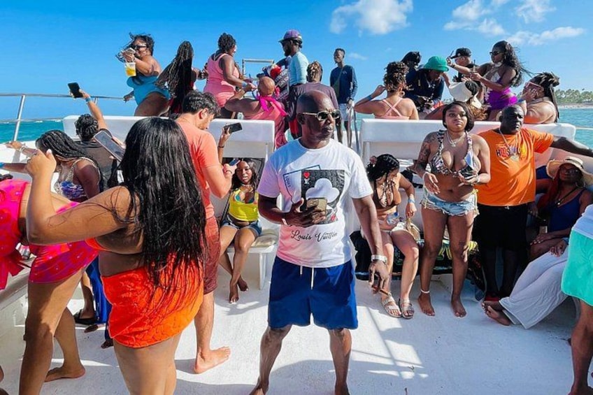 Un groupe de personnes se trouve sur un bateau, certaines sont debout et d’autres sont assises, avec un ciel dégagé en arrière-plan. 4