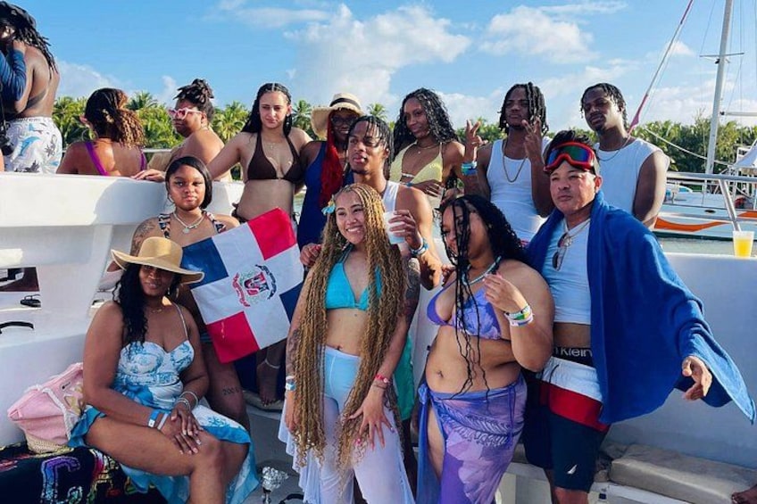 Un groupe de personnes à bord d’un bateau, avec un drapeau, dans un cadre tropical et sous un ciel dégagé. 3
