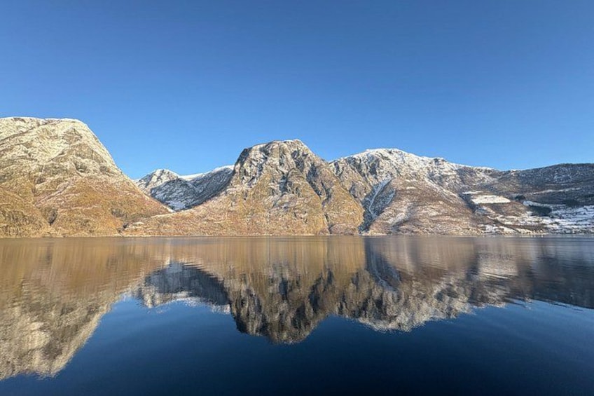 Ein ruhiger See mit klaren Spiegelungen von Bergen, einem wolkenlosen Himmel und weiter Ferne. 4