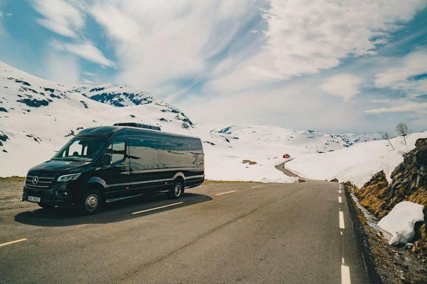 Ein schwarzer Van steht auf einer verschneiten Straße, im Hintergrund sind Berge zu sehen. 3