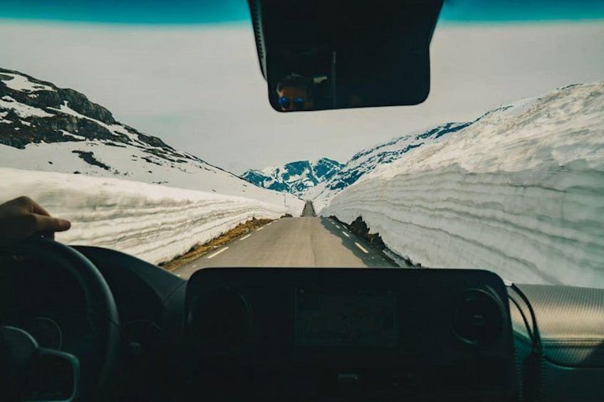 Das Interieur eines Fahrzeugs, durch die Windschutzscheibe ist eine verschneite Berglandschaft zu sehen. 5