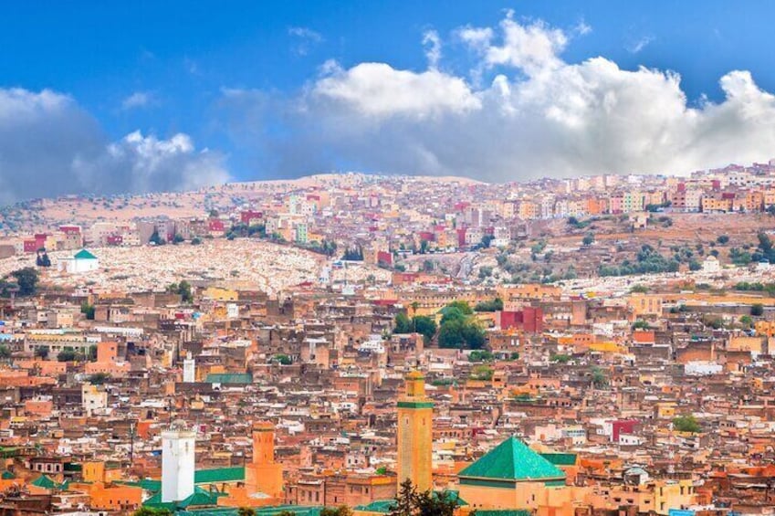 Un paisaje urbano con una mezquita destacada, una torre y una colina al fondo. 1