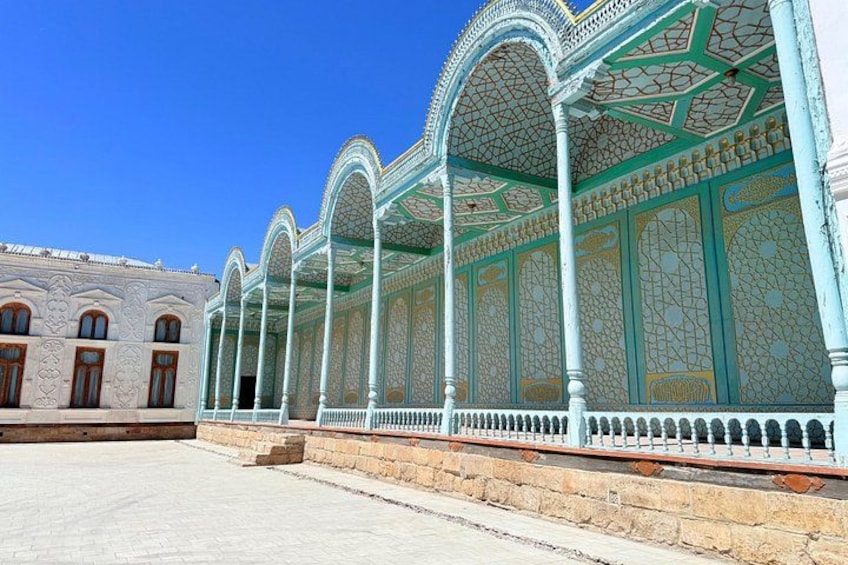 A courtyard with a series of arches and columns, a tiled floor, and a clear blue sky. 3