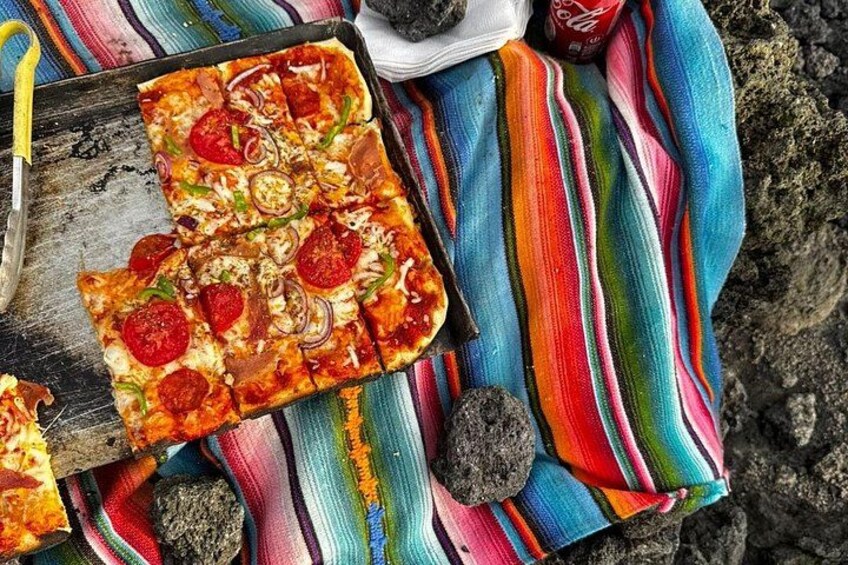 A pizza on a colorful striped cloth with a knife and a soda can nearby. 3