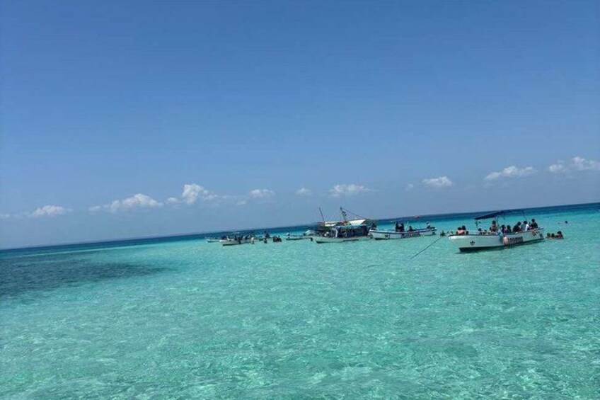 A turquoise sea with several boats and people on them. 2